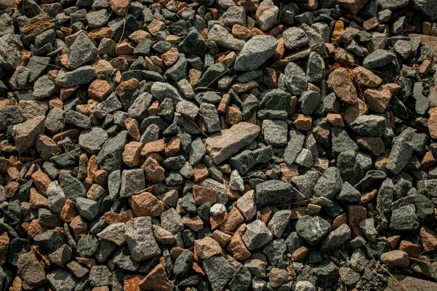 Crushed stone aggregate close up — angular grey and tan pieces in mixed sizes.