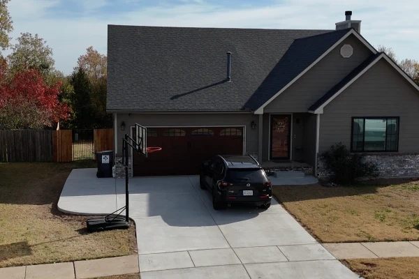 The Debroata house from the street after the pour: the new drive and walk across the full frontage, the car parked at the garage.