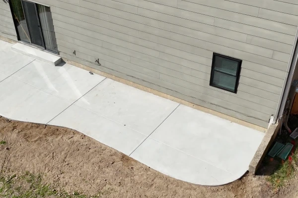 The new service walkway running down the side of the house to the HVAC unit, poured clear of the lawn.
