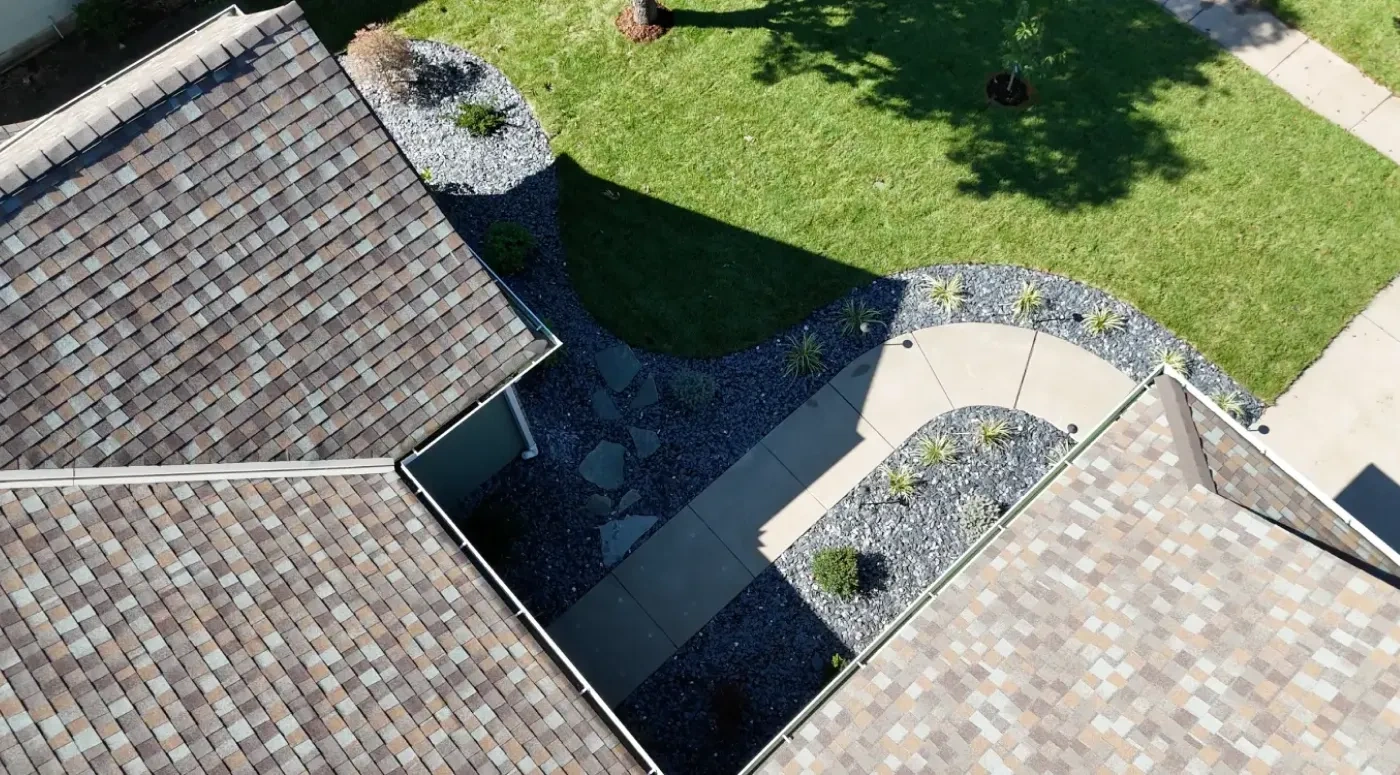 The finished Kumar Residence front landscape from above, with curved slate rock beds held by aluminium edging and a repaired lawn running to the walkway.