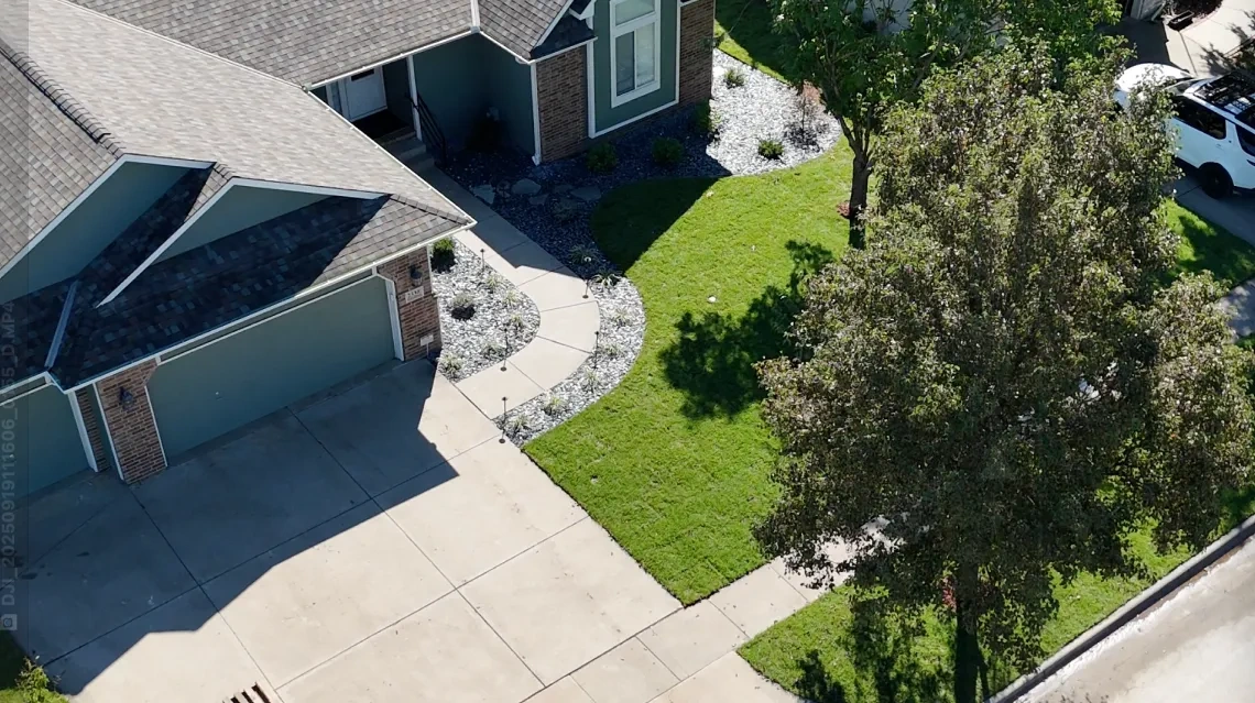The finished Kumar frontage from above, with a new walkway curving to the door, slate rock beds either side of it and a mature tree kept in place.