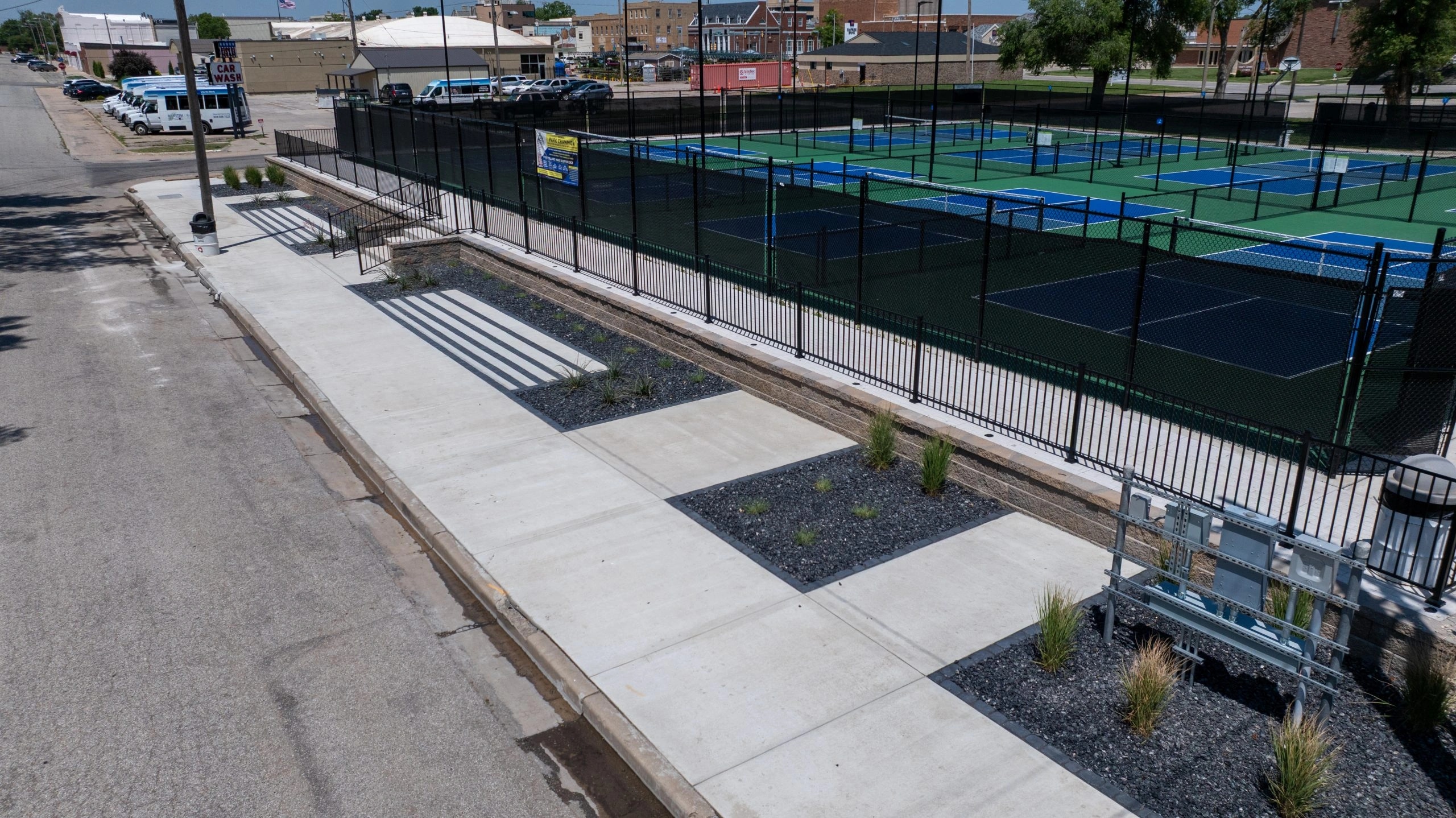 Aerial view of the finished McPherson Commons entry: concrete walkways, paver surfaces and planting beds leading into the pickleball courts.