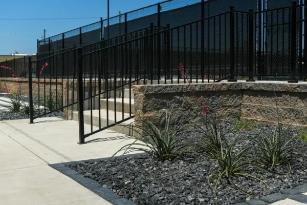 The McPherson entry steps and iron railing, with red yucca in black rock at the foot of the block wall.