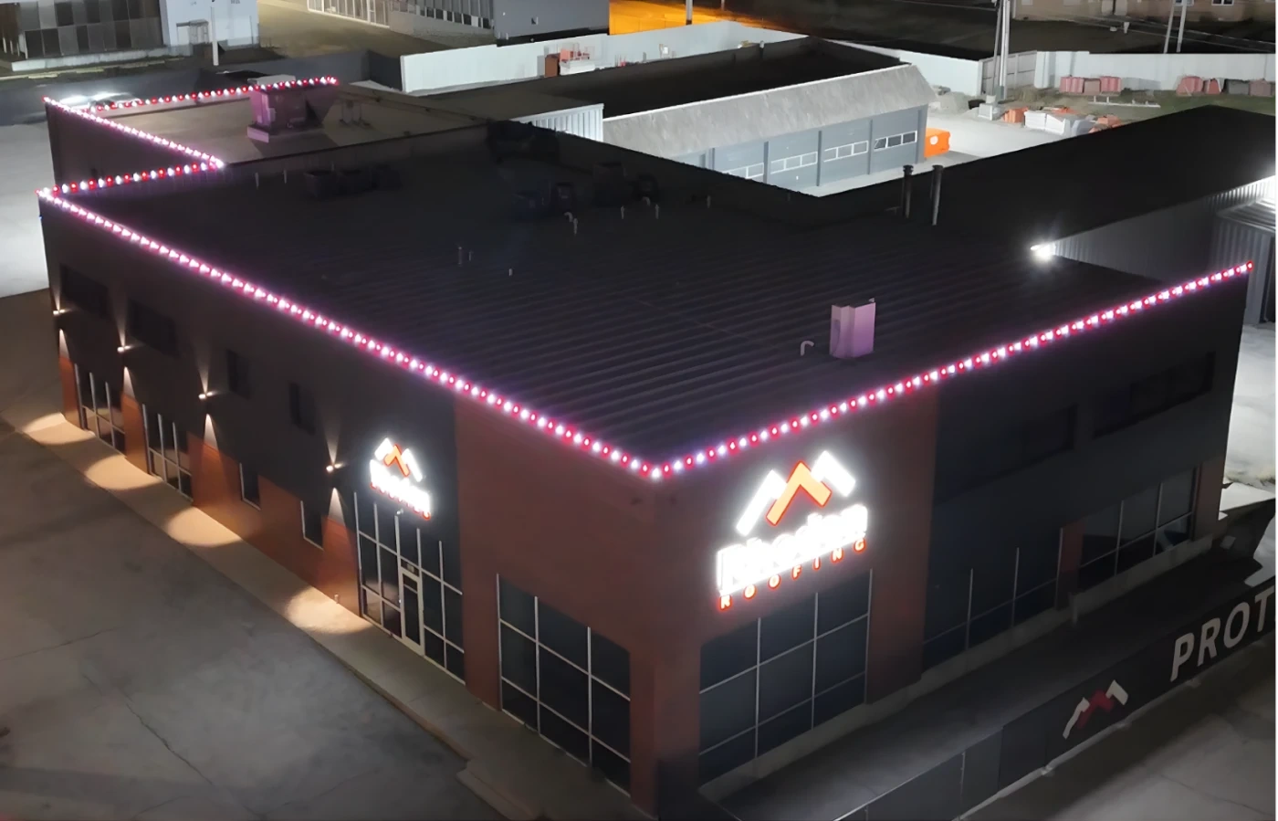 The Rhoden Roofing building at night, its rooflines outlined in commercial Christmas lighting installed by Earthworks.