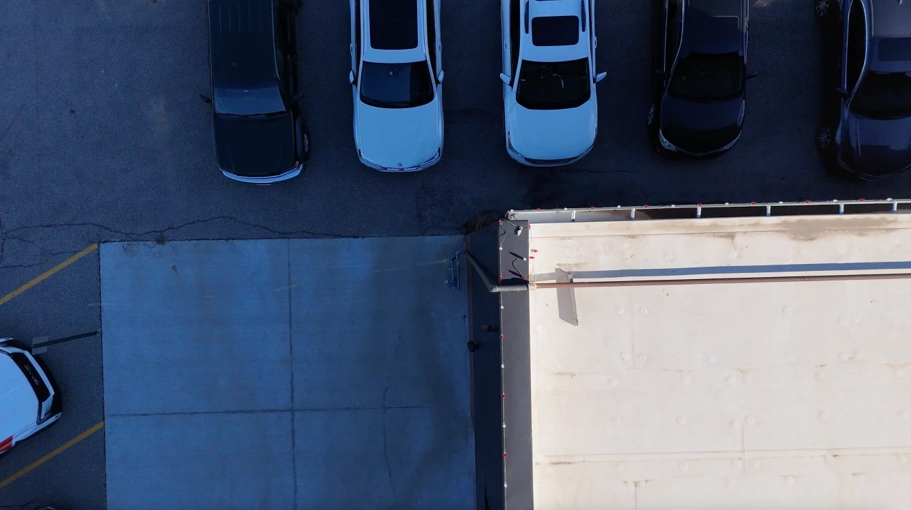Looking straight down on the roof edge at Rhoden Roofing, the lamp run clipped along the parapet in a single line above the car park.
