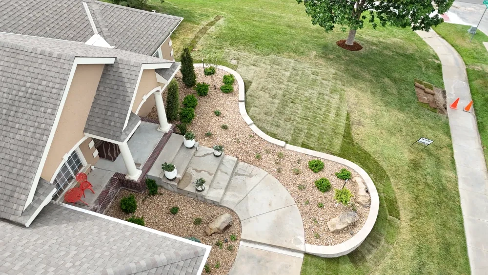 The Riley entry from above the porch: rock beds either side of the steps, the low block wall following the curve of the bed, and new sod reaching to the sidewalk.