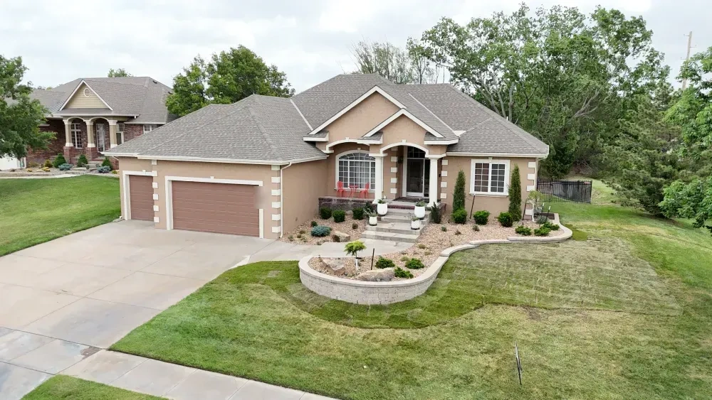 The Riley residence from the street: columnar junipers and rounded evergreens in decorative rock along the house, the raised block planter in front and new sod to the drive.