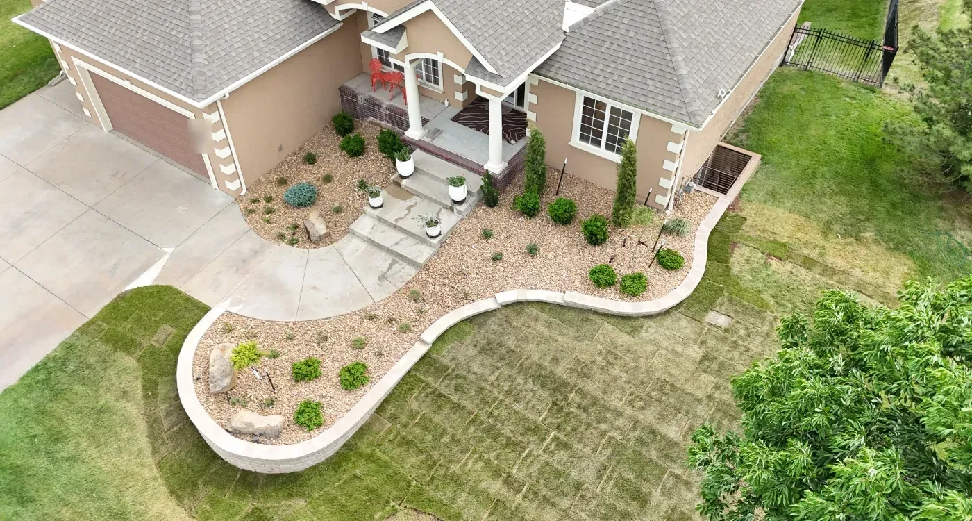 The Riley residence from above: decorative rock beds either side of the front steps, a low capped block wall curving into a raised planter, and new sod in the lawn.
